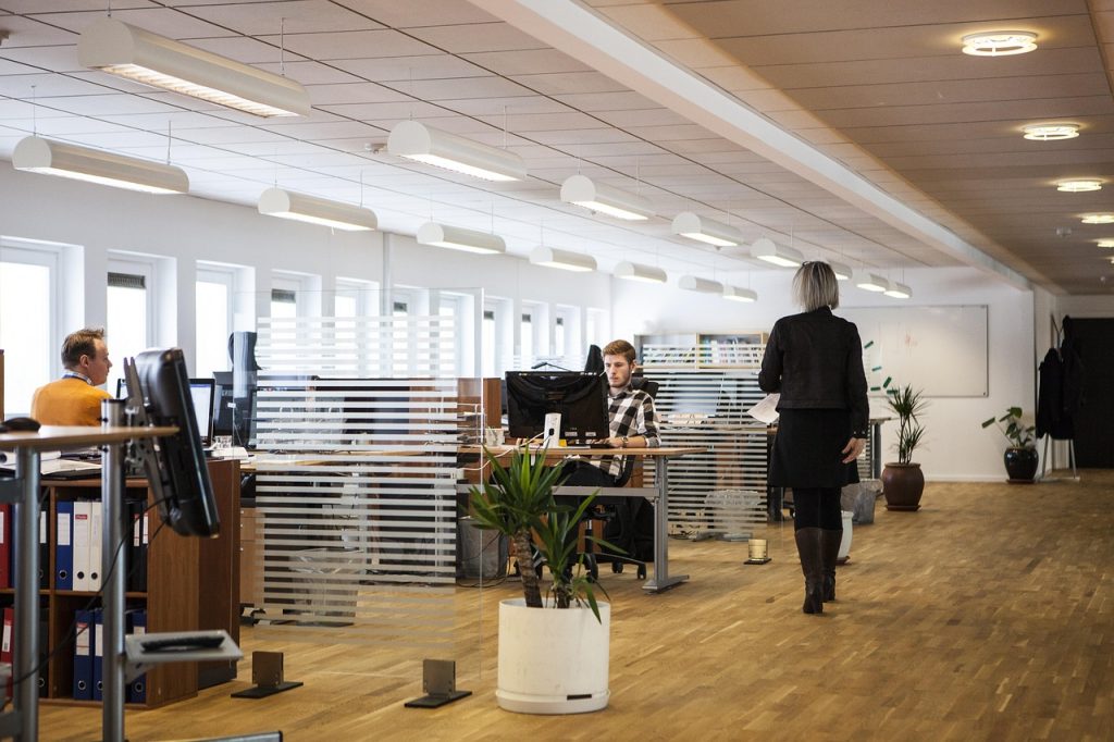 Image actuelle : Open space de bureau moderne avec employés travaillant sur ordinateurs et collègue marchant dans l'allée